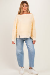 woman wearing a light yellow ribbed maternity sweatshirt with a relaxed fit and paired with light blue jeans