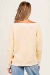 woman wearing a light yellow off-shoulder maternity sweater with a relaxed fit and long sleeves