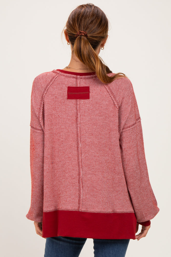 woman wearing a red striped oversized sweater with a solid red hem and back detail, styled with jeans