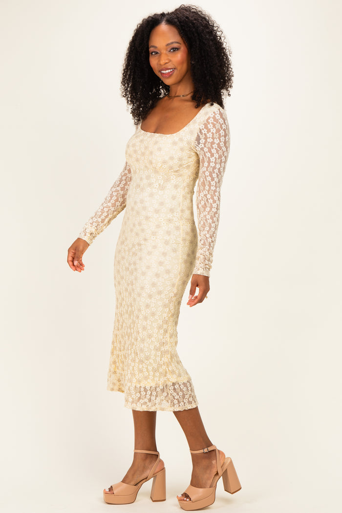 woman wearing a gold sequin long sleeve midi dress with a scoop neckline and sheer lace sleeves