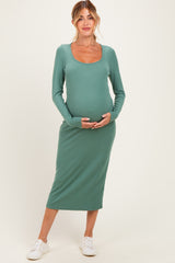 woman wearing a green ribbed long sleeve maternity dress and holding her baby bump