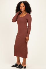 woman wearing a rust brown long sleeve ribbed maxi dress and black mules, posing with one hand on her shoulder
