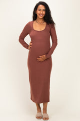 woman wearing a rust long sleeve maternity dress and holding her baby bump