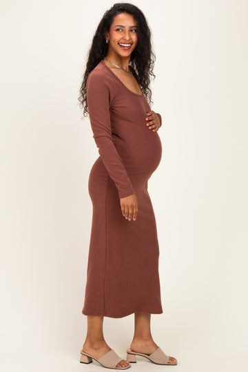 woman wearing a rust long sleeve maternity dress, showing off her baby bump, smiling while standing sideways