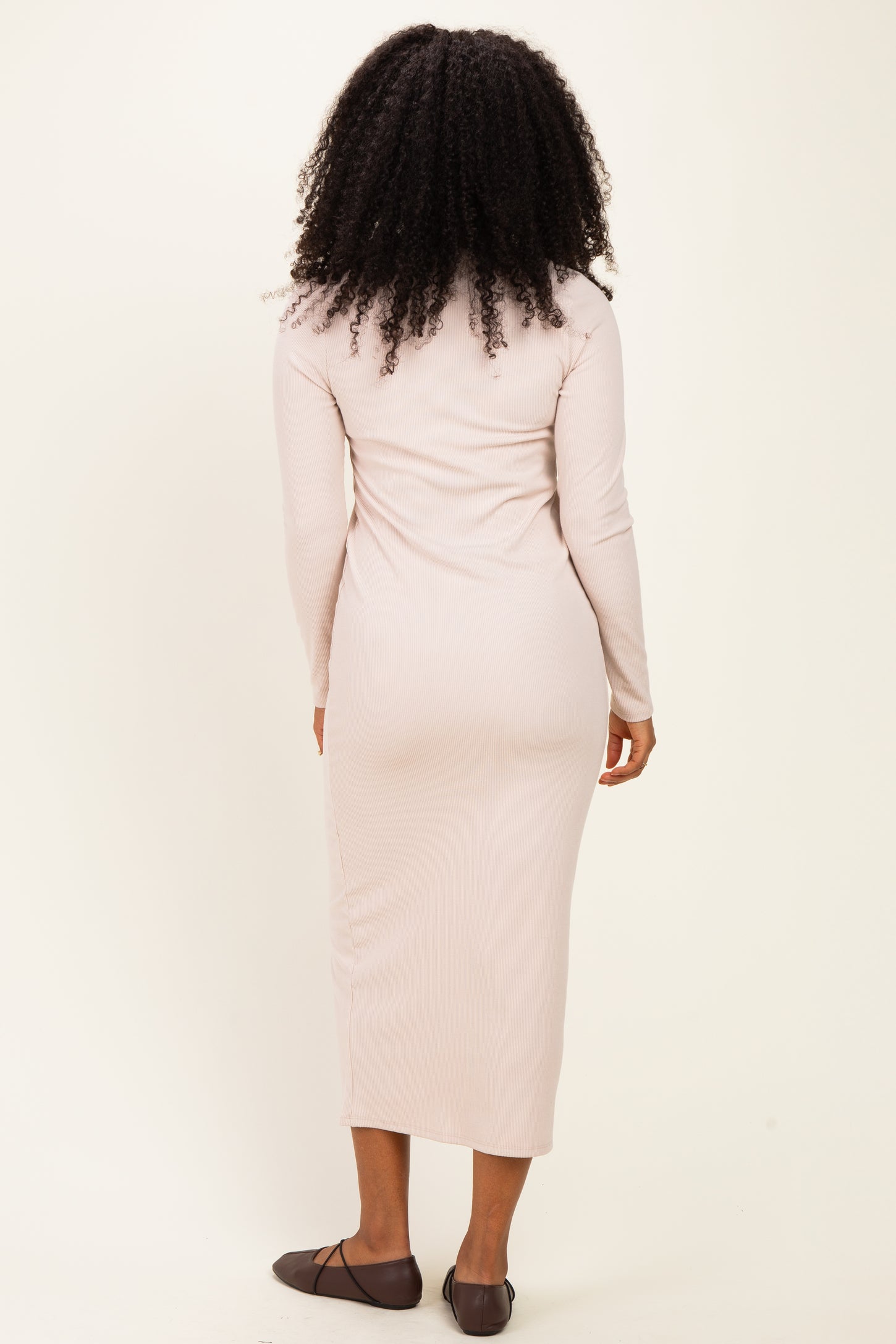 woman wearing a long sleeve ribbed midi dress in light beige, viewed from the back
