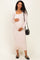 woman wearing a light pink long sleeve maternity dress and holding her baby bump while carrying a small black bag