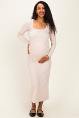 woman wearing a pink ribbed maternity dress with a square neckline and holding her baby bump