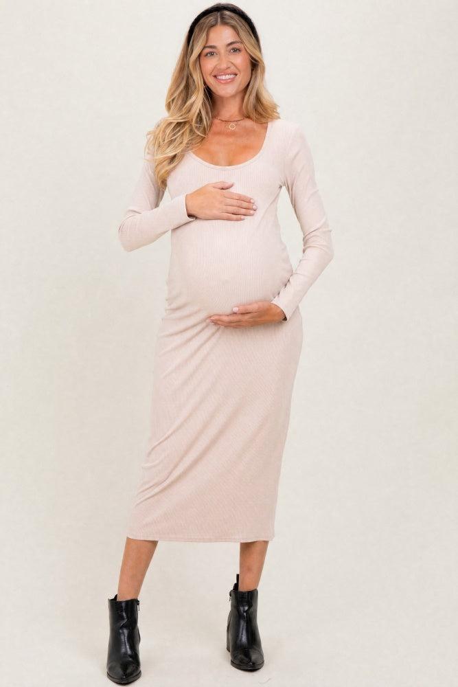 woman wearing a beige long sleeve maternity dress and holding her baby bump