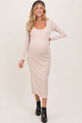 woman wearing a beige long sleeve maternity dress with a scoop neckline and a visible baby bump