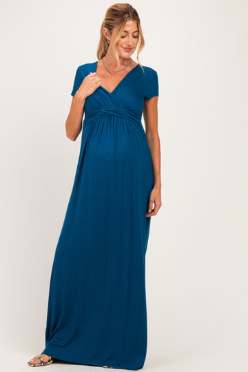 woman wearing a teal short sleeve maternity maxi dress, showcasing her baby bump and a flattering wrap design