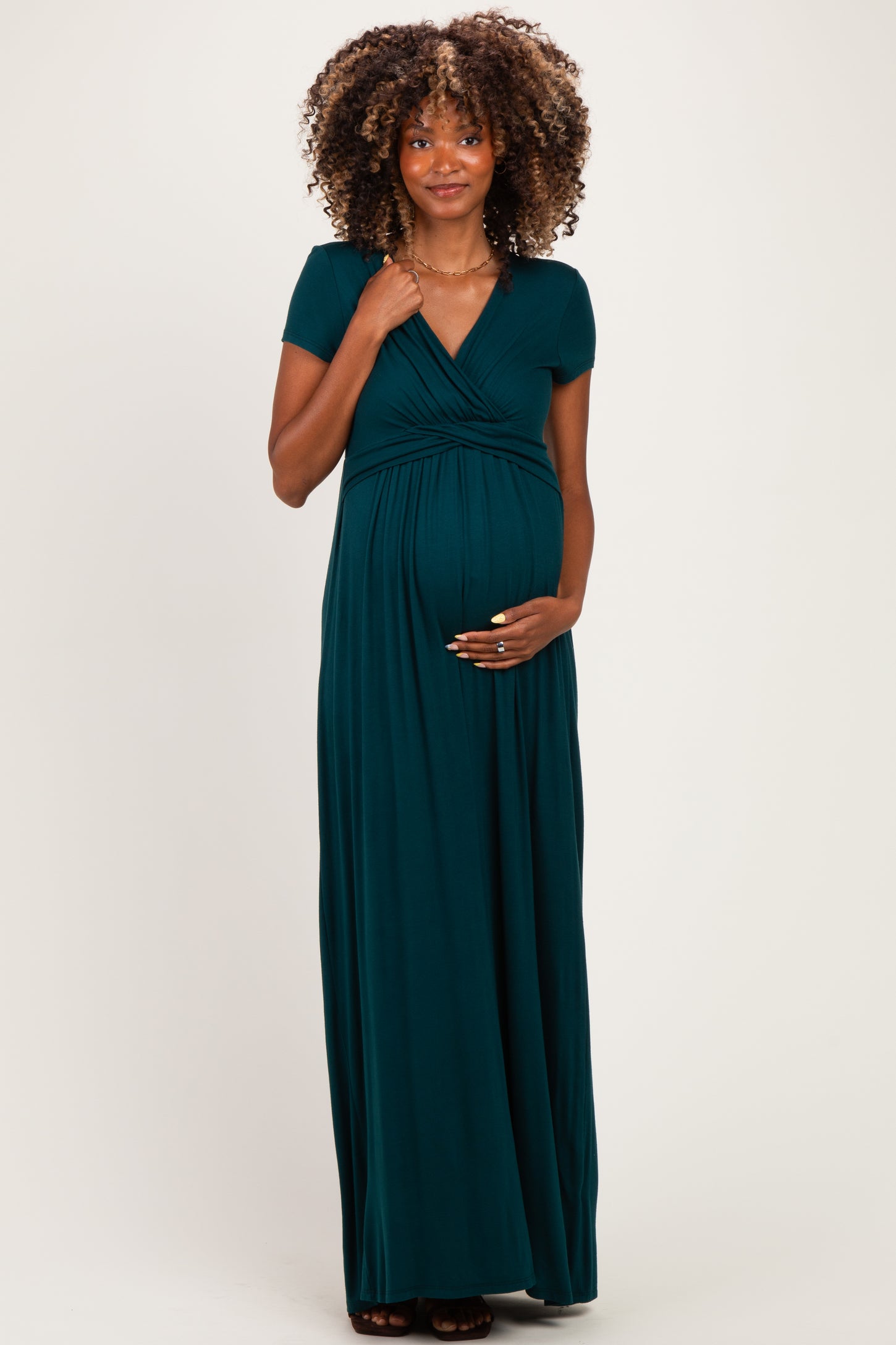 woman wearing a dark green short sleeve maternity maxi dress and holding her baby bump