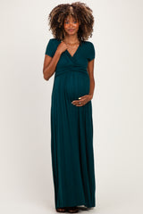 woman wearing a dark green short sleeve maternity maxi dress and holding her baby bump