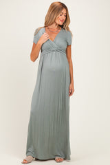 woman wearing a sage green short sleeve maternity maxi dress with a v-neck and a visible baby bump