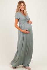 woman wearing a green short sleeve maternity maxi dress and holding her baby bump