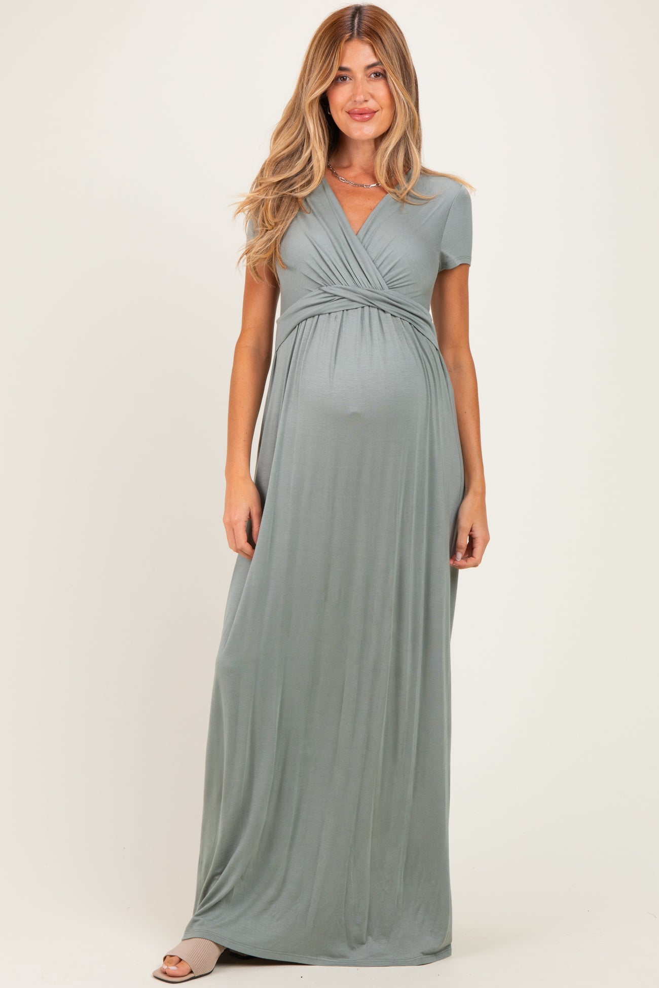 woman wearing a teal short sleeve maternity maxi dress with a gathered waist and visible baby bump