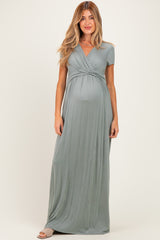 woman wearing a teal short sleeve maternity maxi dress with a gathered waist and visible baby bump