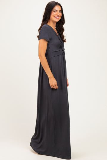 woman wearing a dark gray maxi dress with short sleeves and a twisted front detail standing sideways