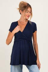 woman wearing a navy blue short sleeve maternity top with a wrap style and highlighted baby bump