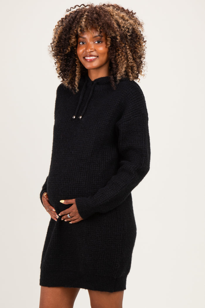 woman wearing a black maternity hoodie dress and holding her baby bump