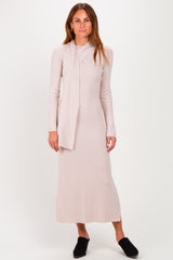 woman wearing a light beige long sleeve ribbed maxi dress with a tie detail and black slip-on shoes