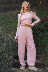 woman wearing a light pink long sleeve cropped top with matching blush joggers and sneakers, standing outdoors