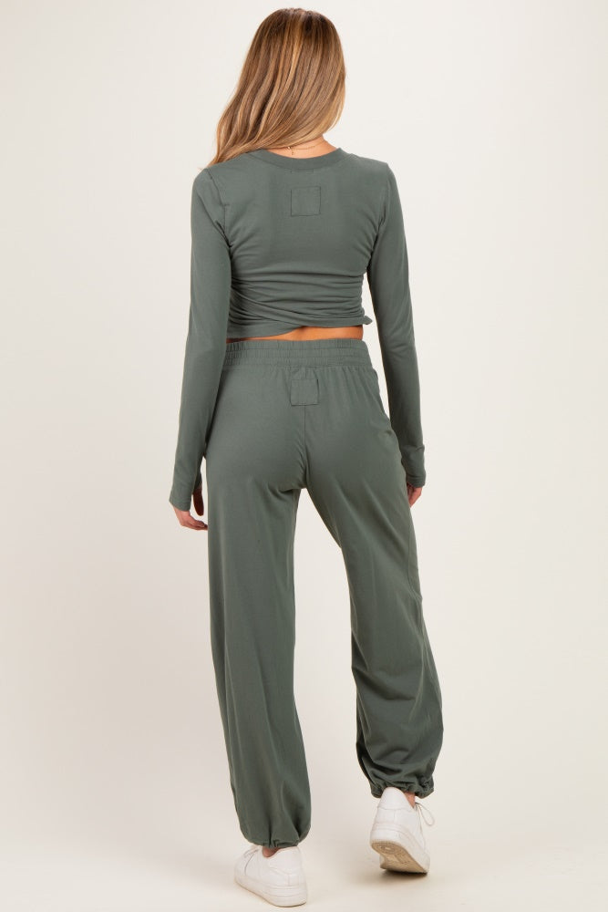 woman wearing a green long sleeve cropped maternity top and matching high-waisted pants, showing a relaxed fit