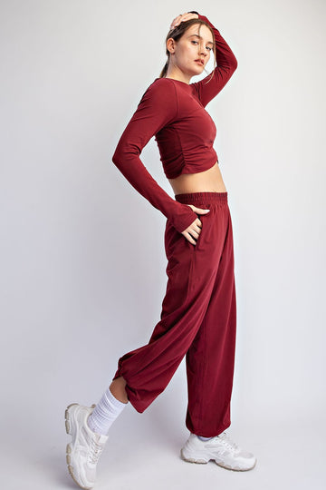 woman wearing a burgundy long sleeve crop top and matching loose-fit pants paired with white sneakers
