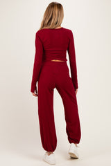woman wearing a burgundy maternity long sleeve top and matching jogger pants, showing the back view