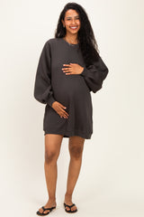 woman wearing a dark grey maternity sweatshirt dress and holding her baby bump