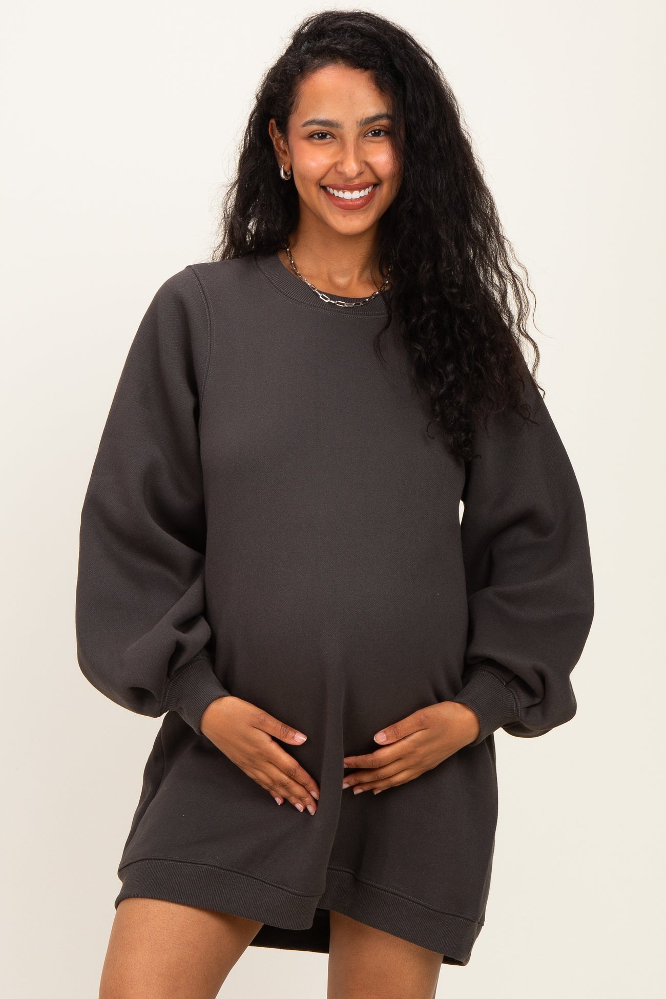 woman wearing a charcoal gray maternity sweatshirt dress and holding her baby bump