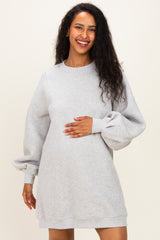 woman wearing a gray maternity sweatshirt dress with long balloon sleeves and holding her baby bump