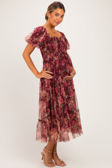 woman wearing a burgundy floral maxi maternity dress with short sleeves and a visible baby bump
