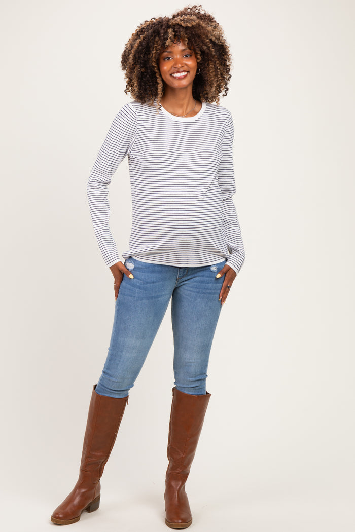 woman wearing a striped maternity top with long sleeves and blue jeans, showing off her baby bump