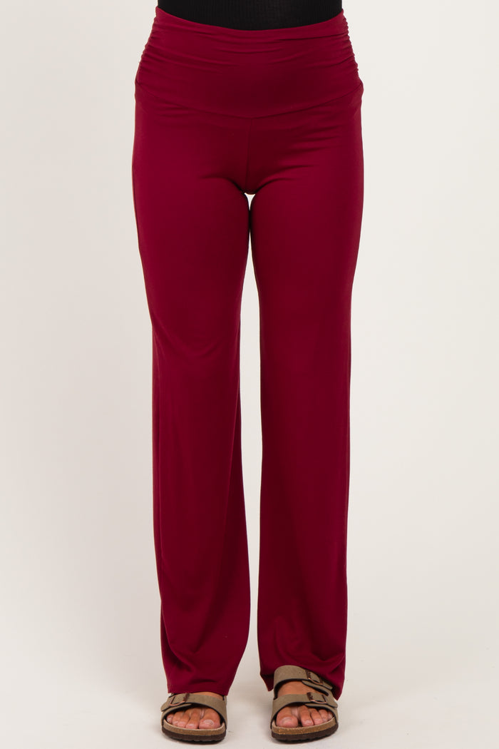 woman wearing burgundy maternity pants with a wide waistband and a relaxed fit