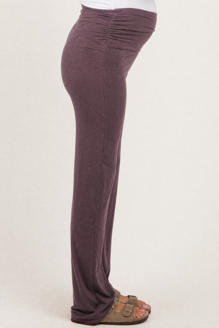woman wearing a purple maternity pant with ruched details and a visible baby bump