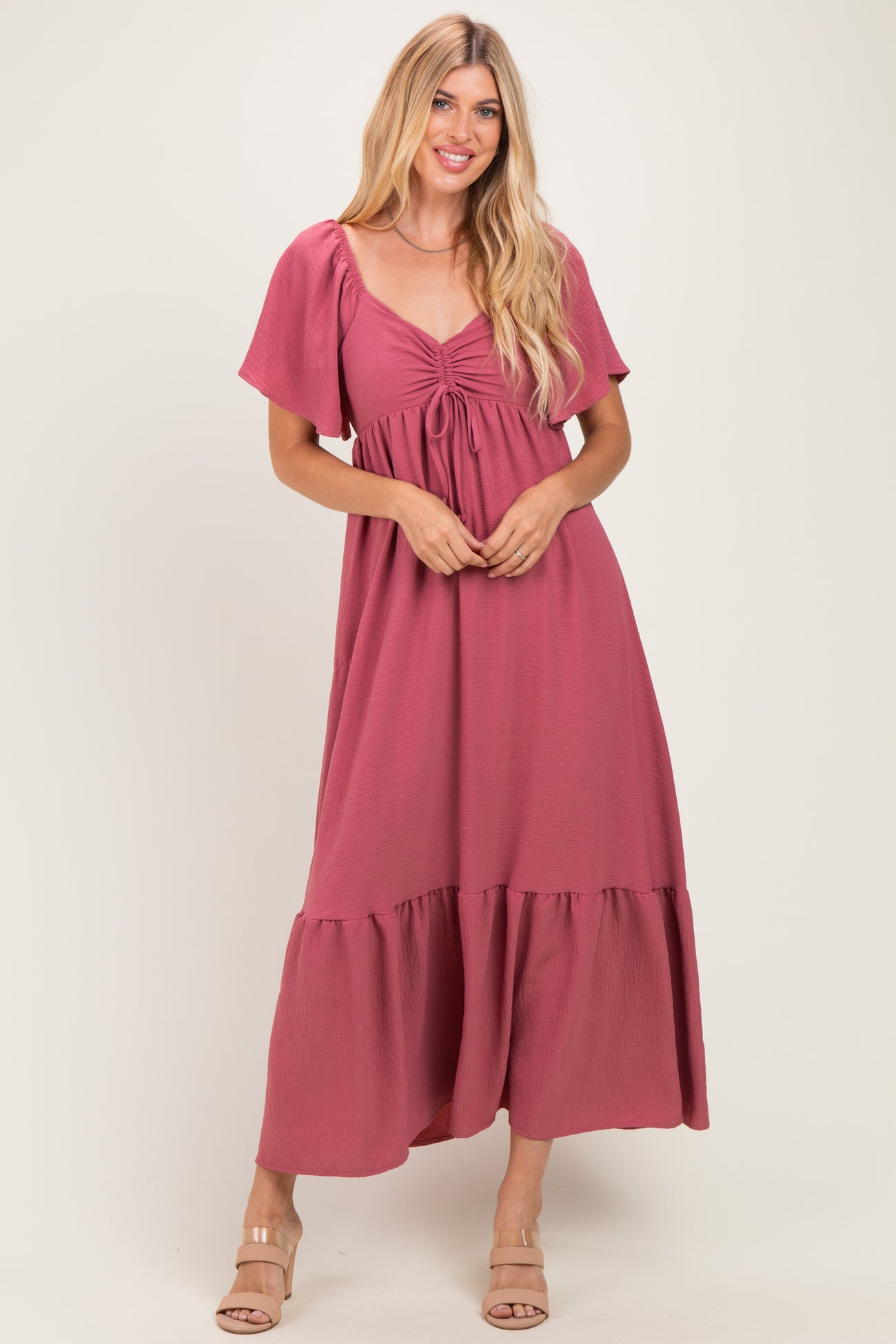woman wearing a mauve maxi dress with short sleeves, gathered v-neckline, and a tiered skirt