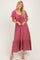 woman wearing a mauve maxi dress with short sleeves, gathered v-neckline, and a tiered skirt