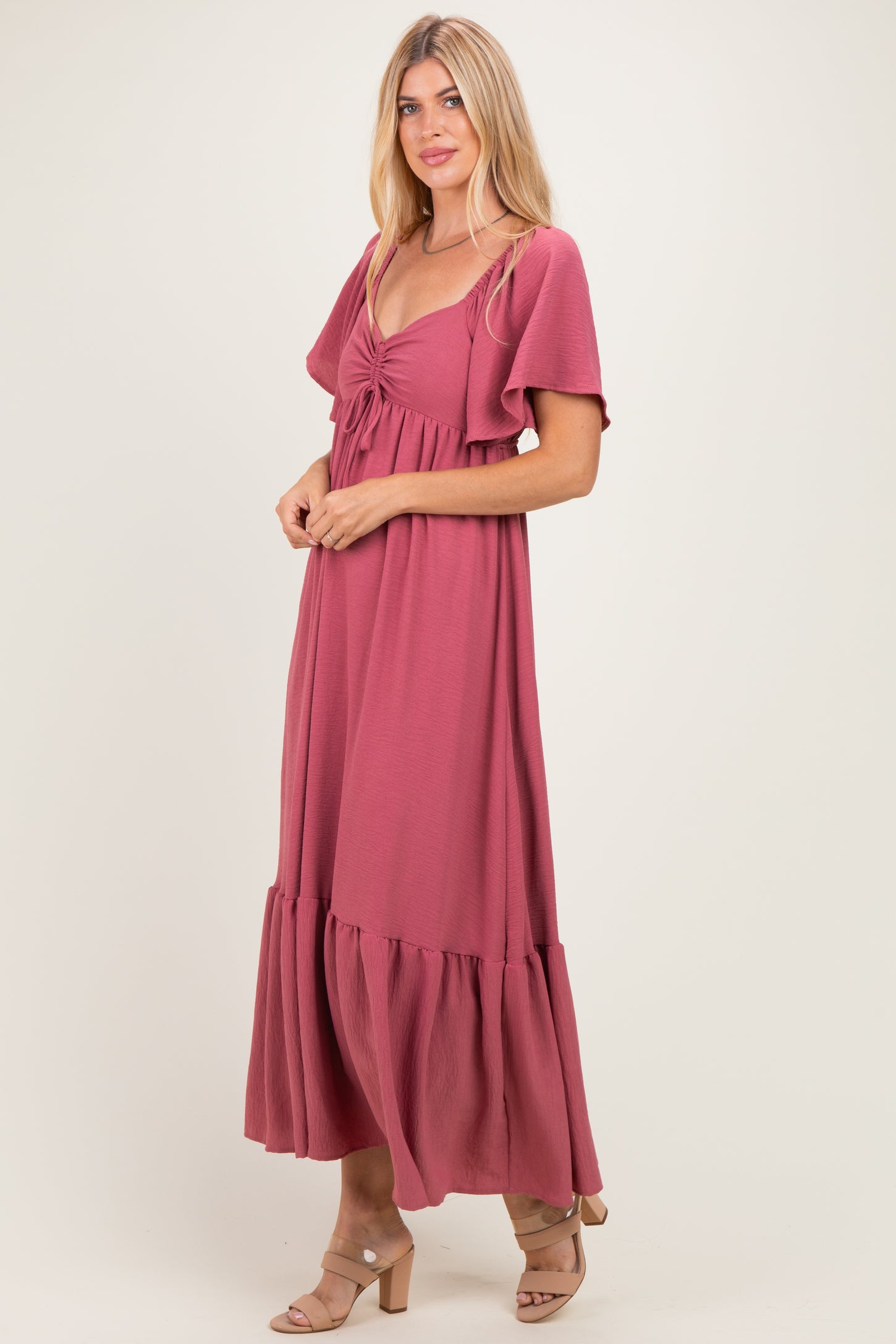 woman wearing a dusty rose maxi dress with flutter sleeves and a tie-front detail