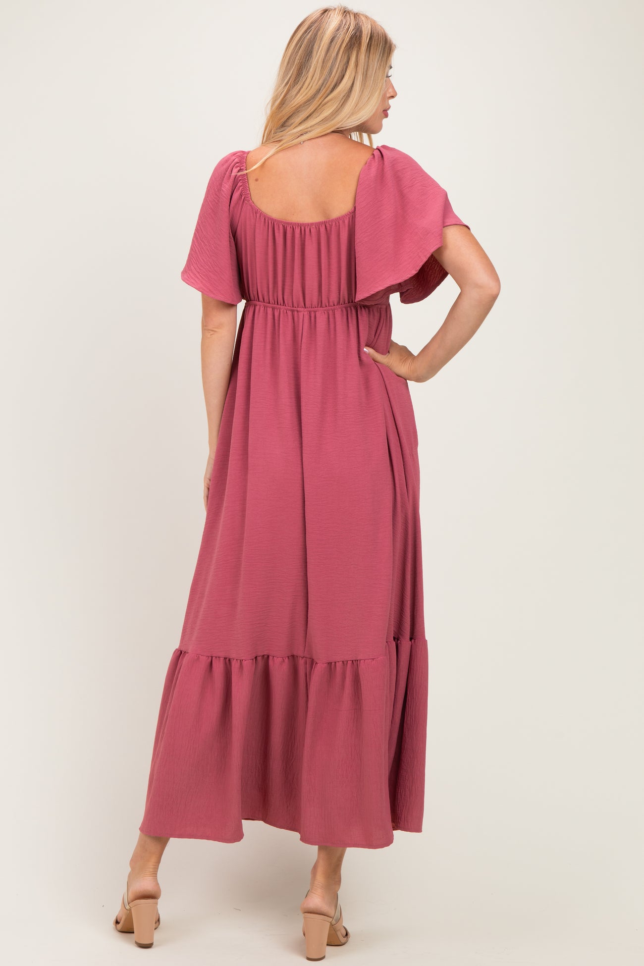 woman wearing a mauve maxi dress with flutter sleeves and a tiered hem, shown from the back