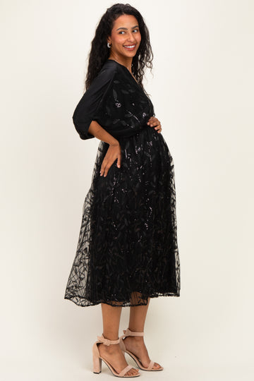 woman wearing a black maternity dress with floral sequin overlay and a visible baby bump