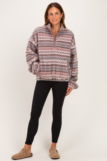 woman wearing a cozy patterned fleece pullover in pink and gray with black leggings and tan slip-on shoes