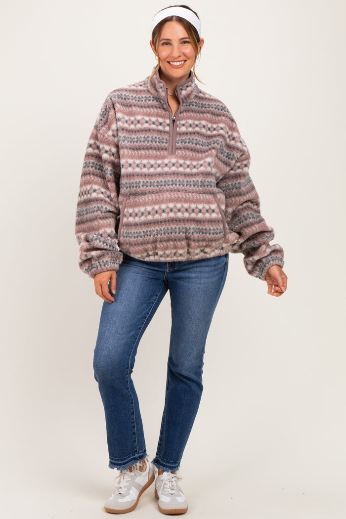 woman wearing a patterned fleece maternity pullover and blue jeans with a baby bump visible
