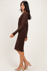 woman wearing a fitted brown long sleeve dress with lace detail and heels, standing sideways