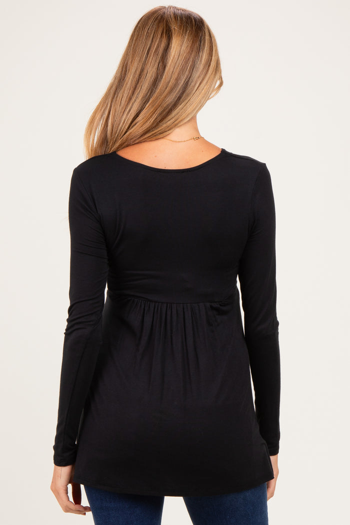 woman wearing a black long sleeve maternity top with a gathered waist detail, showing her back