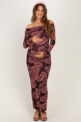woman wearing a dark floral off-the-shoulder maternity dress and holding her baby bump