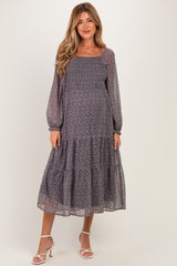 woman wearing a floral print maternity maxi dress with long sleeves and a tiered skirt, showing her baby bump