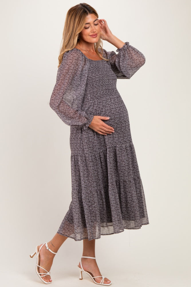 woman wearing a floral print long sleeve maternity dress with a tiered skirt, showing her baby bump
