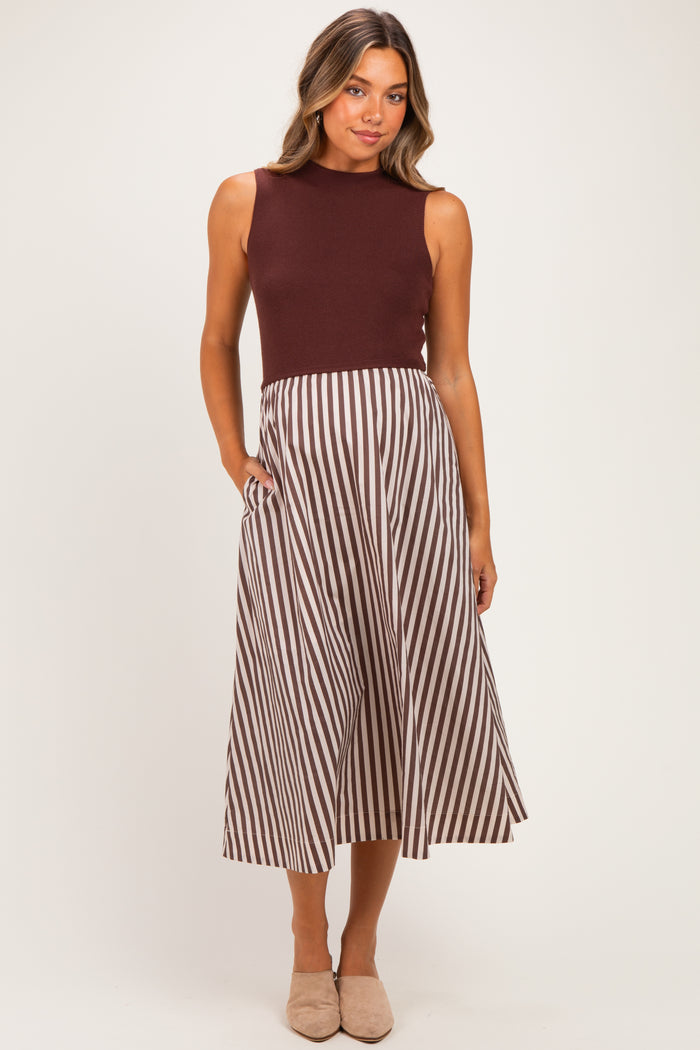woman wearing a burgundy sleeveless top and a brown and white striped maternity skirt with pockets, showing her baby bump