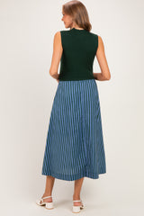 woman wearing a green sleeveless maternity dress with a blue striped skirt, showing a slight baby bump from the back
