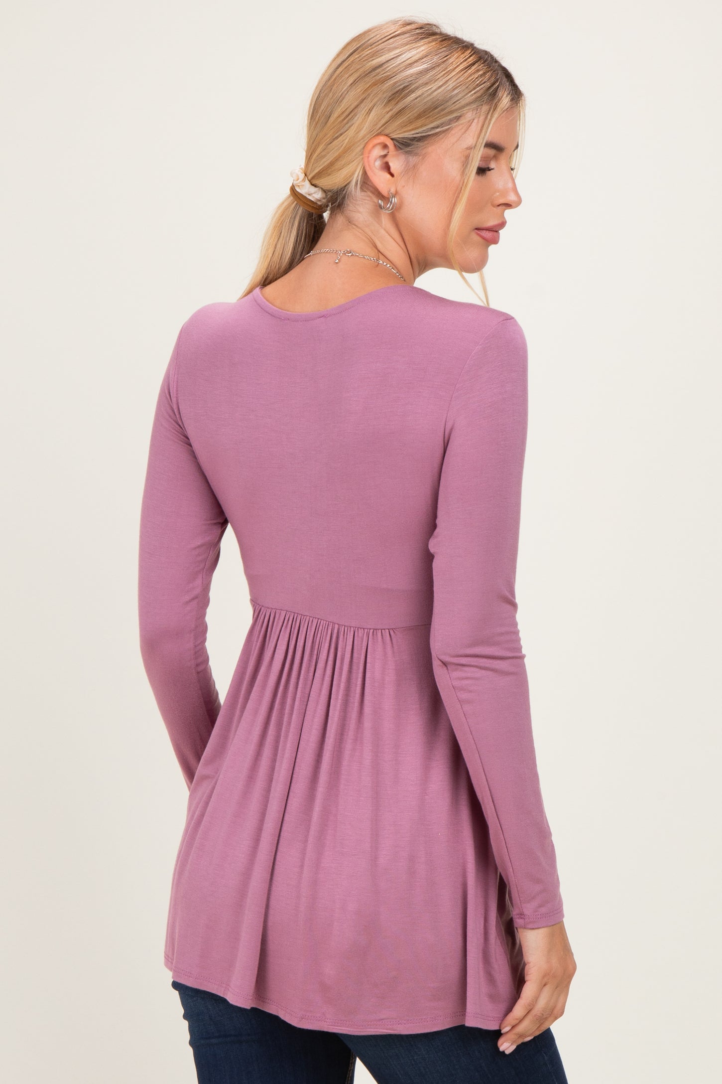 woman wearing a mauve long sleeve top with a gathered waist, viewed from the back